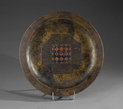 une assiette marron ornée d'un motif, posée sur un support en métal