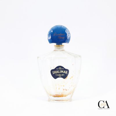 un vieux flacon de parfum posé sur une surface blanche