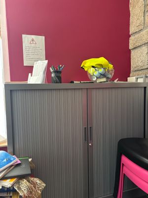 une chaise rose posée devant un mur rouge