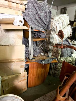 a pile of boxes and a chair in a room filled with furniture