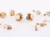 several pairs of gold and pearl earrings on a white surface