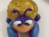 a small toy crab with a gold ball on it ' s back