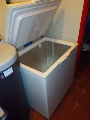 un réfrigérateur blanc et une poubelle noire placés l'un à côté de l'autre