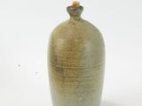 a green vase with a brown lid sitting on a white surface