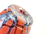 a glass vase that has a red and blue design on it