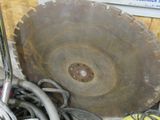 une photo montrant une grande lame de scie posée sur une pile d'autres outils