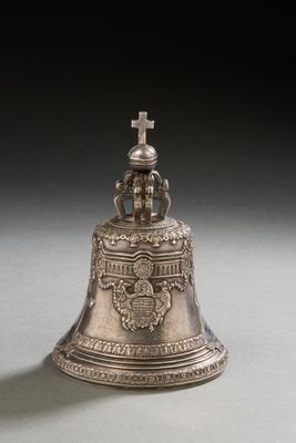 an old silver bell with a cross on top sitting on a table