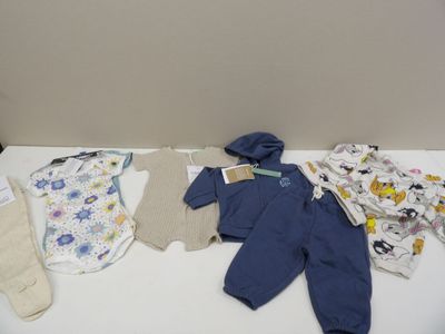 une table blanche sur laquelle sont posés des vêtements pour bébés et des moufles
