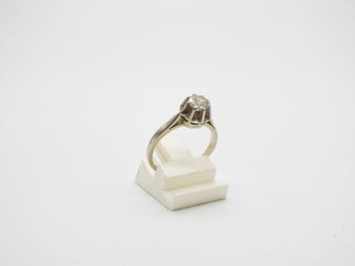 une bague en or blanc et diamants posée sur un bloc de marbre blanc