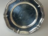 une assiette en argent posée sur une table, sur fond blanc