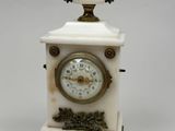 une petite horloge blanche surmontée d'un oiseau