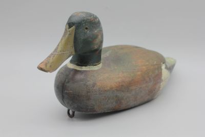 un gros plan d'un canard en bois posé sur une surface blanche