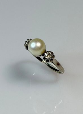pearl and diamond ring on a white surface