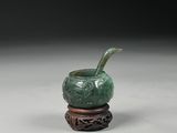 une image représentant un vase vert posé sur un socle en bois