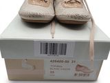 une paire de chaussures beiges posée sur une boîte portant un code-barres sur le côté