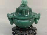 green jade buddha incense burner on a stand on a white surface