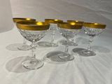 quatre verres à vin aux bords dorés posés sur une table blanche