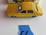 une petite voiture jaune posée à côté d'une étiquette bleue