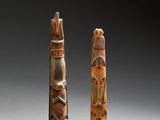 two carved wooden sculptures of a man and woman on a pedestal