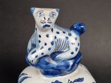 a blue and white cat sitting on top of a bell
