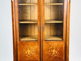 une vieille armoire en bois avec une porte vitrée, posée sur un parquet en bois massif