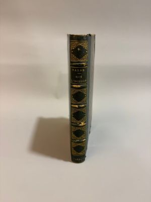 an old book sitting on top of a white table next to a white wall