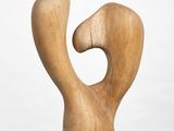 sculpture of a wooden figure on a white pedestal against a white background