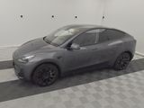the gray tesla suv is parked in the garage of a house