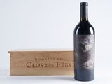 the bottle of wine is next to a wooden box on a white surface