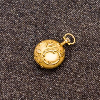 une image représentant une montre de poche en or posée sur un tissu