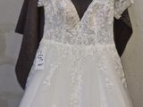 a white wedding dress hanging on a hanger in front of a wall