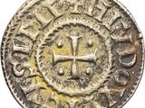 une vieille pièce de monnaie sur laquelle figure une croix, sur fond blanc