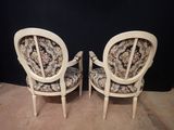 two white chairs with floral upholstered cushions and a black background
