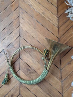 un instrument à vent en laiton posé par terre à côté d'un sapin de Noël