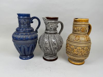 trois vases de couleurs différentes posés les uns à côté des autres sur une surface blanche