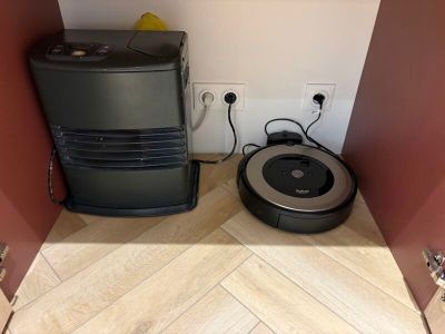 une cuve de cuisson et un aspirateur posés par terre dans un coin de la pièce