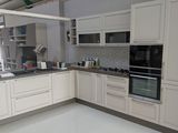 une cuisine avec des placards blancs et une cuisinière-four noire