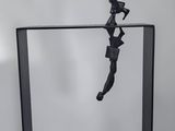 black sculpture of a man jumping through a glass box