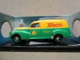une camionnette jouet verte et jaune exposée dans une boîte