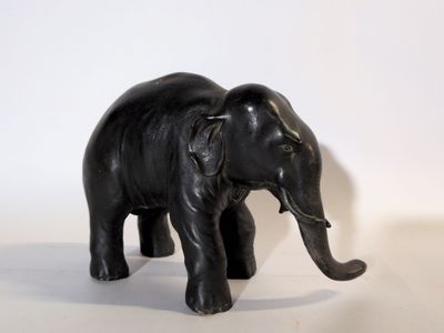 un petit éléphant noir debout sur une surface blanche