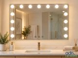 a bathroom vanity with a lighted mirror and a plant
