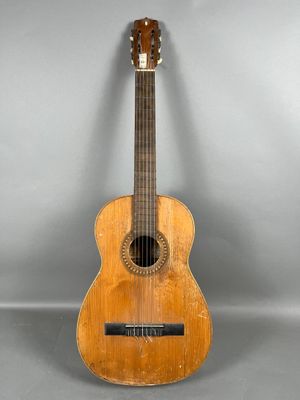 an old wooden guitar sitting on top of a gray surface