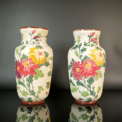 two vases sitting on a table with flowers painted on them