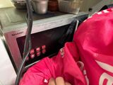a person that is holding a bag in front of a microwave