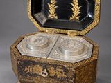 a black and gold box with two silver dishes inside