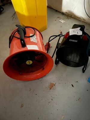 un ventilateur rouge posé par terre à côté d'autres ventilateurs