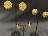 several pairs of gold and silver earrings on a black stand
