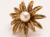 gros plan d'une bague en or avec une perle au centre