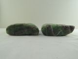 two pieces of green jade sitting on top of a white surface