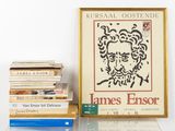 a picture of a picture of james ensor next to a pile of books